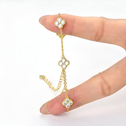 Bracelet maille trèfle porte-bonheur en argent 925 plaqué or jaune et diamants entre les doigts d'une femme vue de face.