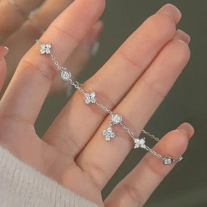Bracelet pendeloque fleur en argent 925 plaqué or blanc et moissanites montré par une main de femme vue de face.