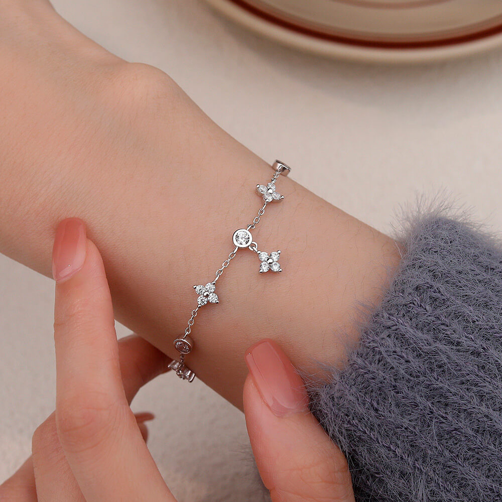 Bracelet pendeloque fleur en argent sterling 925 plaqué or blanc et moissanites porté au poignet d'une femme vue de proche.