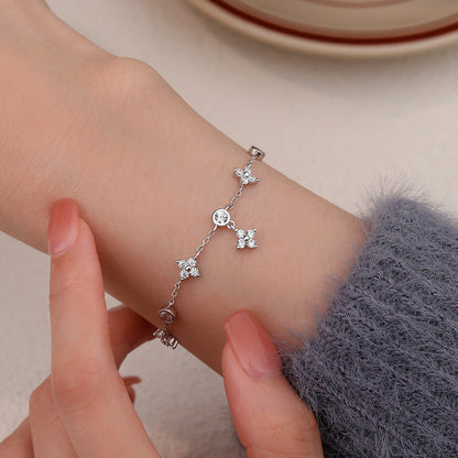 Bracelet pendeloque fleur en argent sterling 925 plaqué or blanc et moissanites porté au poignet d'une femme vue de proche.