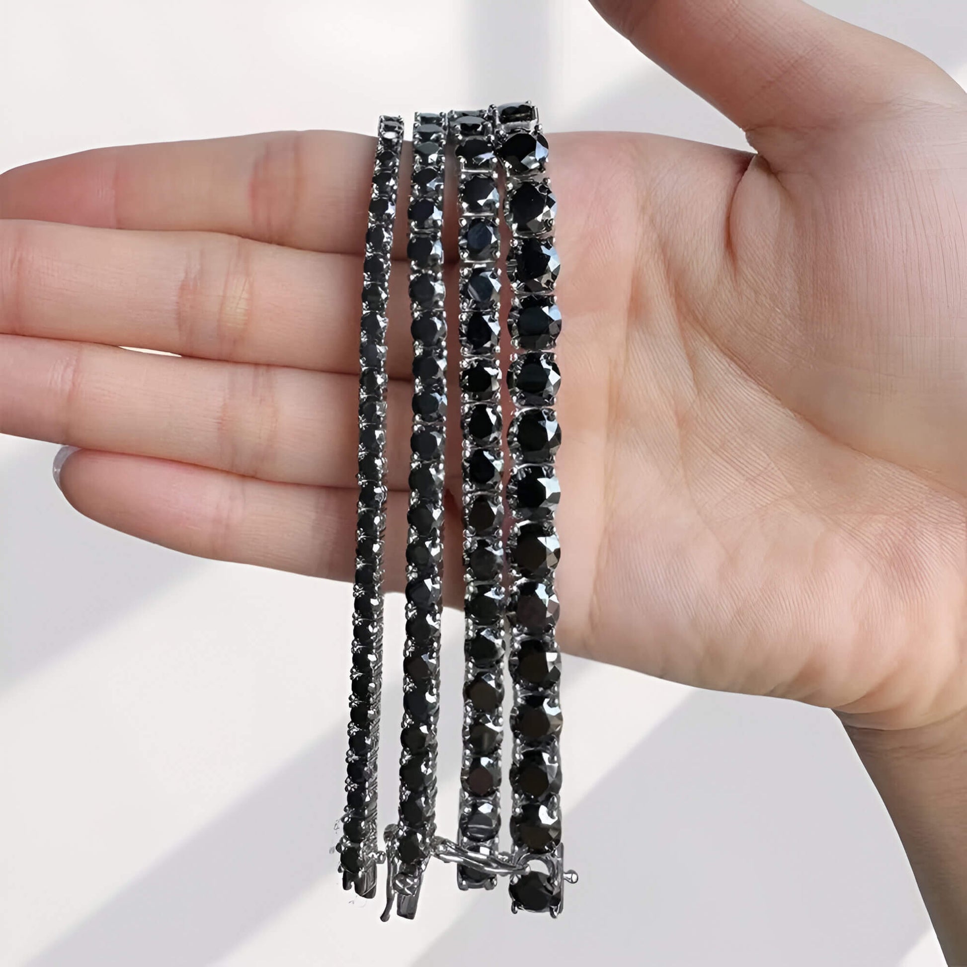 Toutes les variantes Bracelet tennis diamants noirs de moissanite 0.1ct, 0.3ct, 0.5ct et 1ct en argent 925 plaqué or blanc sur une main de femme vue de face.