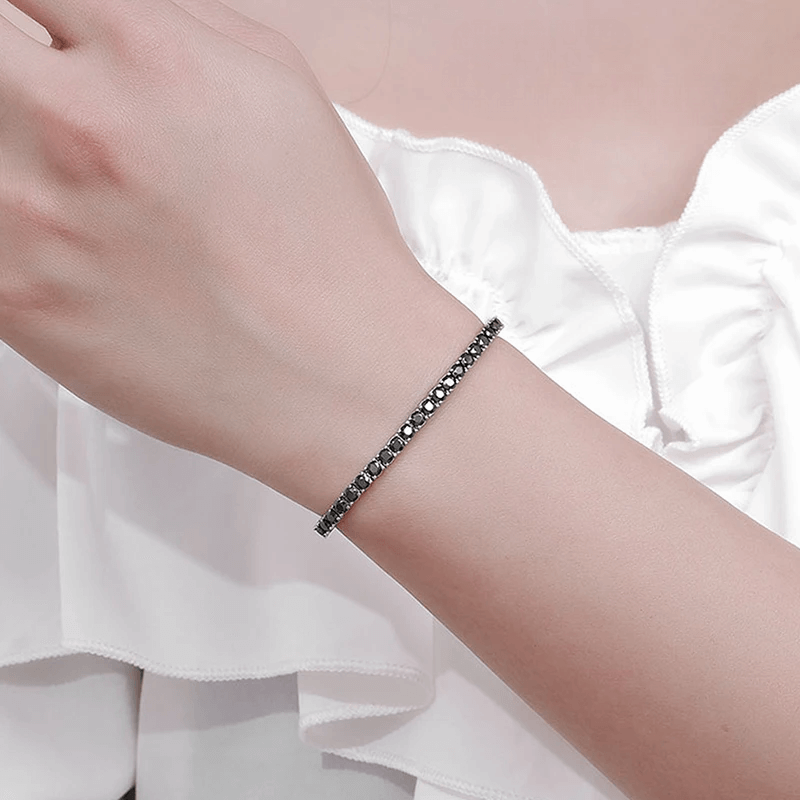 Bracelet tennis diamant noir en argent plaqué or blanc variante 0.1 carat porté au poignet d'une femme.