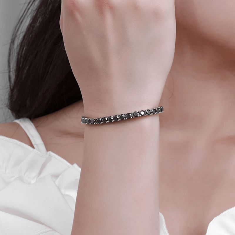 Bracelet tennis diamant noir en argent plaqué or blanc variante 0.3 carat porté au poignet d'une femme.