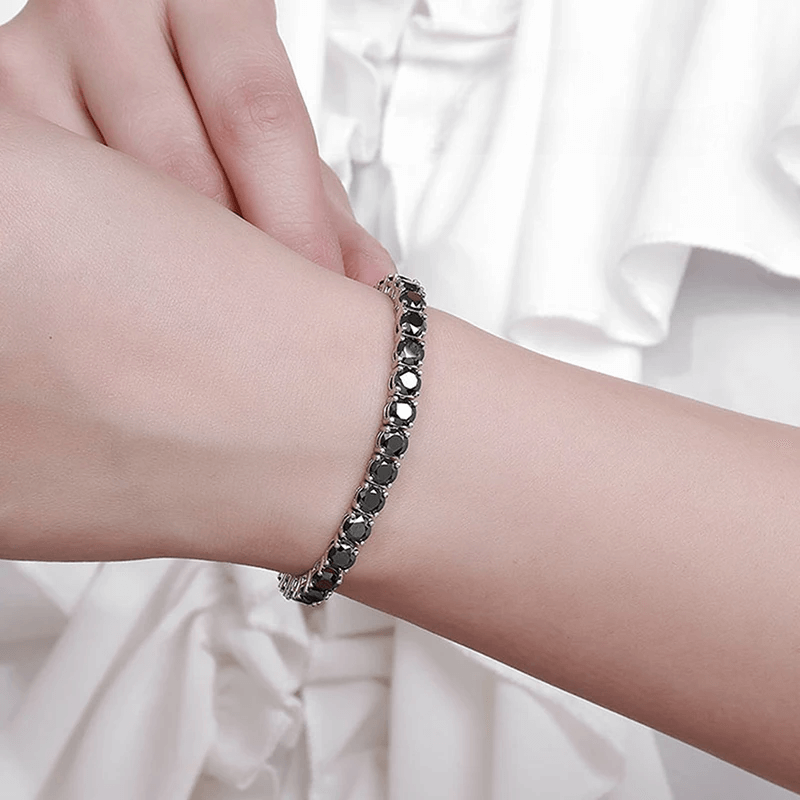 Bracelet tennis diamant noir en argent plaqué or blanc variante 0.5 carat porté au poignet d'une femme.