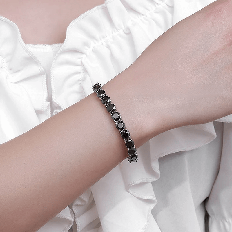 Bracelet tennis diamant noir en argent plaqué or blanc variante 1 carat porté au poignet d'une femme.