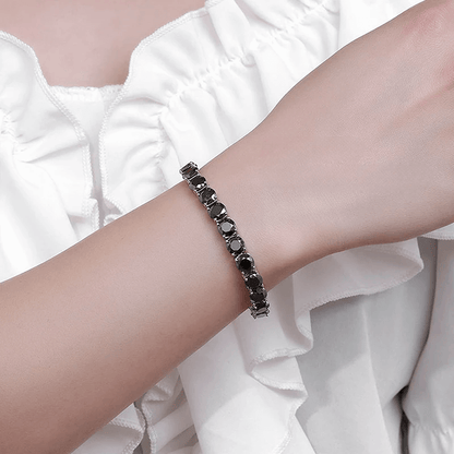 Bracelet tennis diamant noir en argent plaqué or blanc variante 1 carat porté au poignet d'une femme.