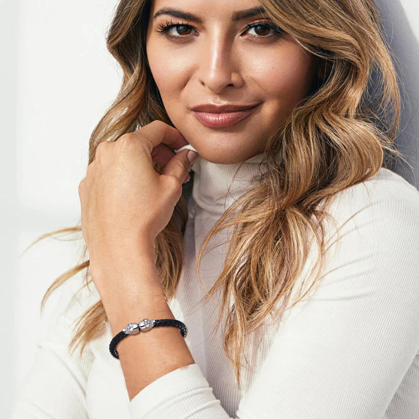 Bracelet tête de mort en cuir tressé noir et acier inoxydable plaqué titane blanc porté au poignet d'une femme.