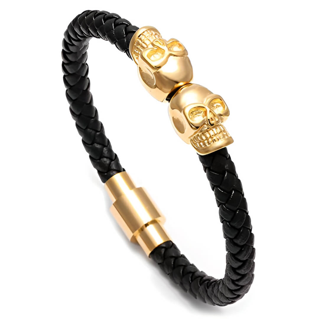 Bracelet tête de mort en cuir tressé noir et acier inoxydable plaqué or jaune sur fond blanc.
