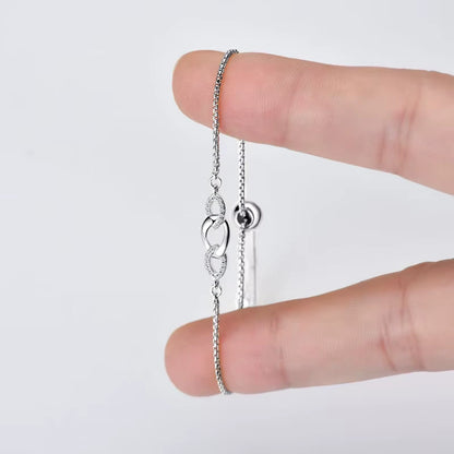 Chaîne amovible nœud en argent plaqué or blanc et diamants synthétiques entre les doigts d'une femme.