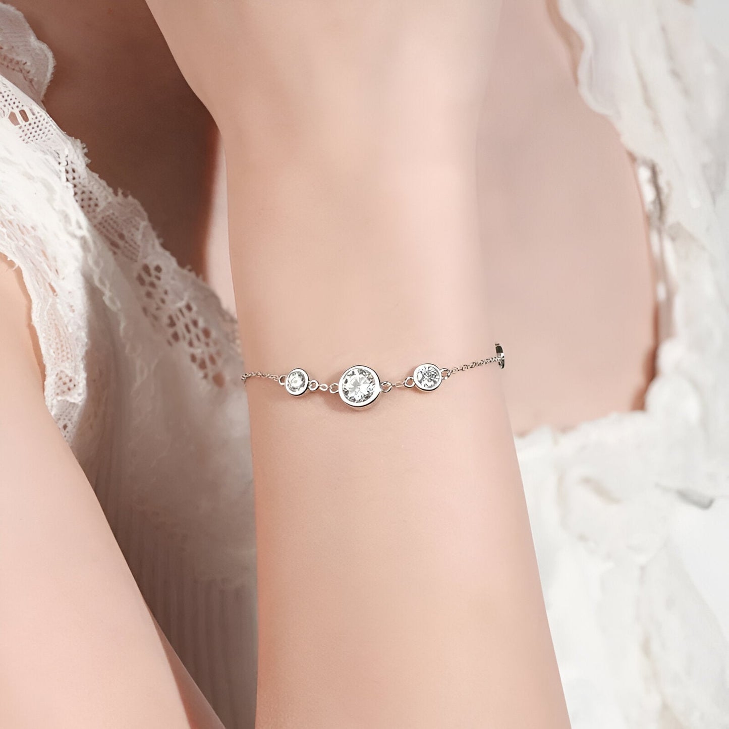 Chaîne cinq pierre en or blanc et diamants synthétiques portée au poignet d 'une femme vue de face.