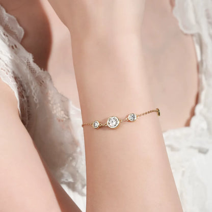 Chaîne cinq pierre en or jaune et diamants synthétiques portée au poignet d'une femme vue de face.