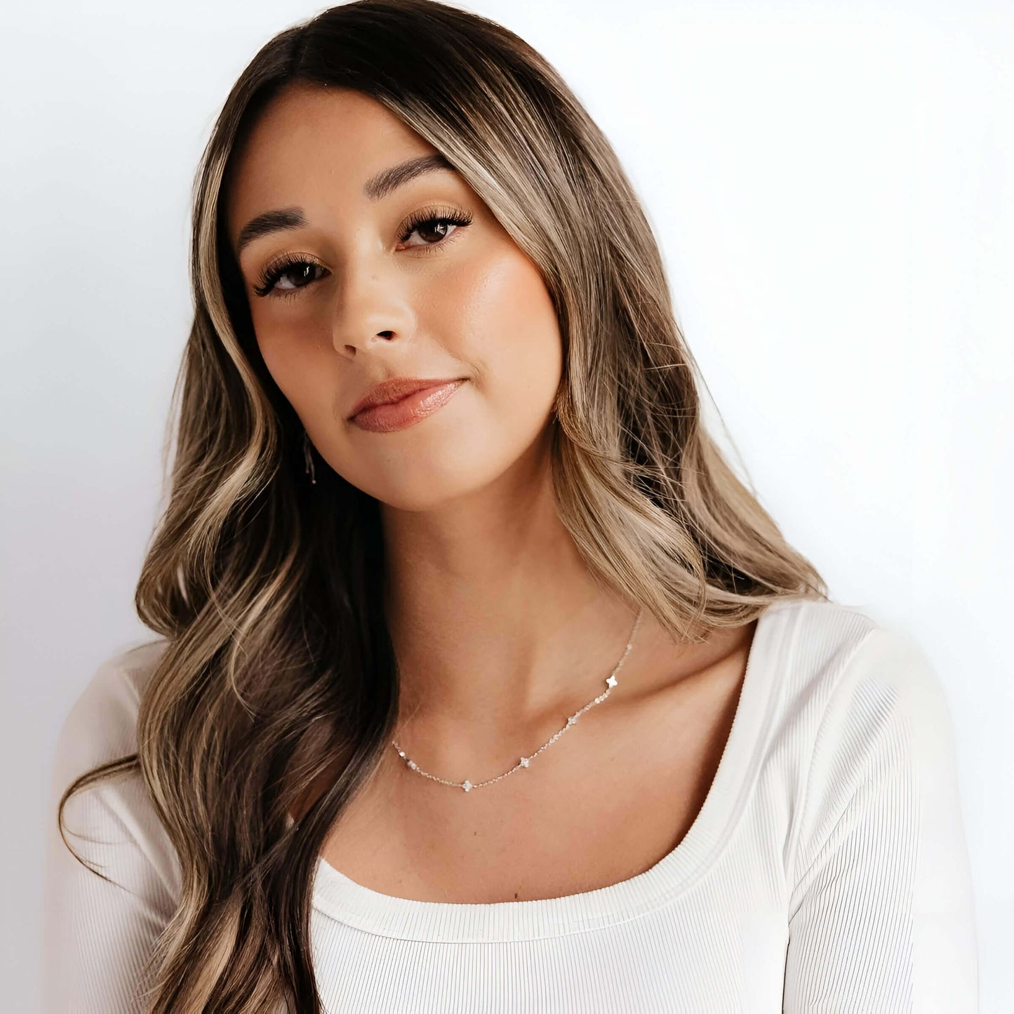 Chaîne fleurs de diamants naturels en or blanc portée au cou d'une femme vue de loin.