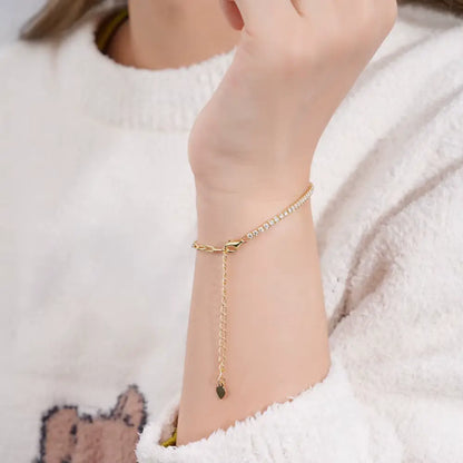 Chaîne maille cheval en or jaune et diamants synthétiques portée au poignet d'une femme.