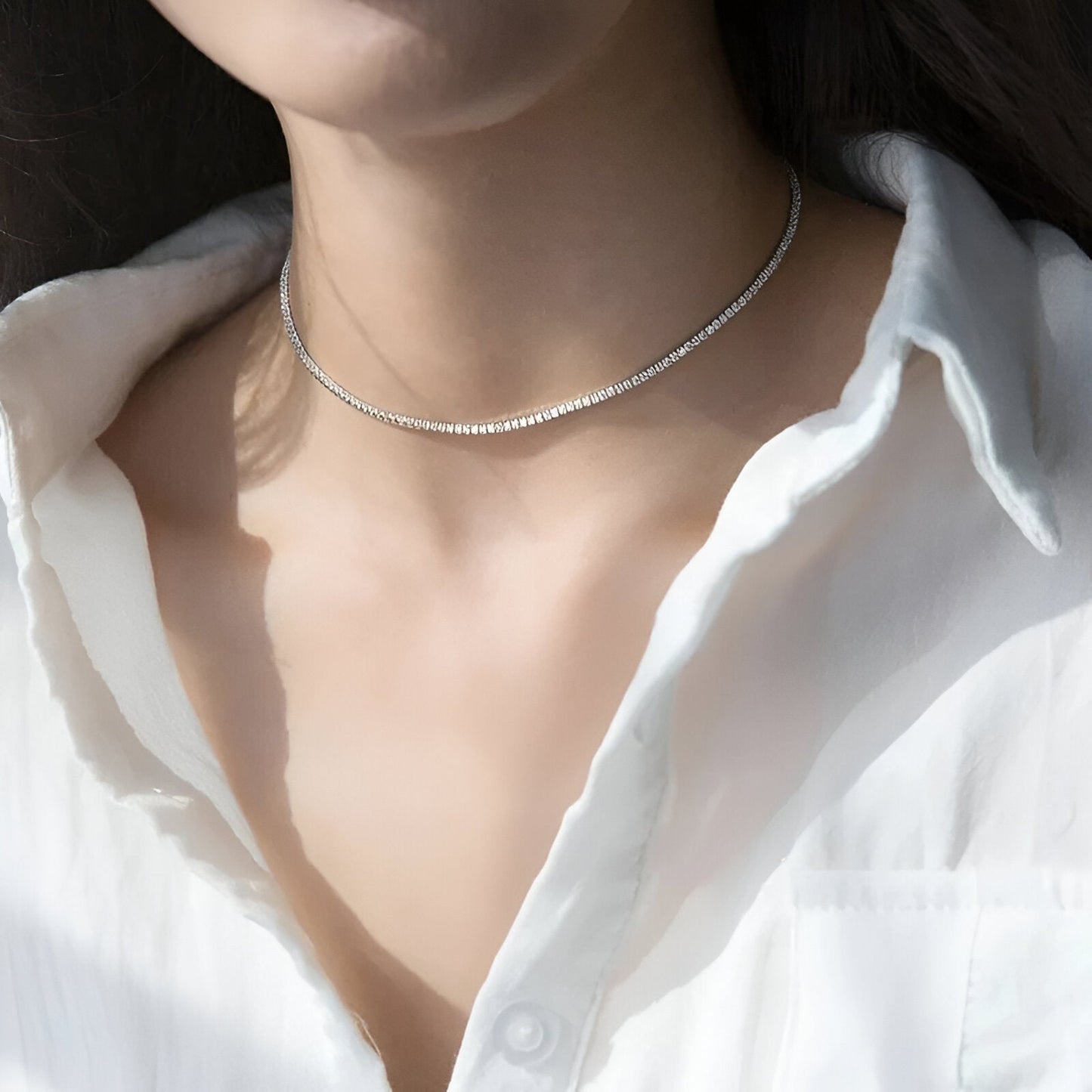 Chaîne pavé de diamants synthétiques / diamants naturels en or blanc portée au cou d'une femme.