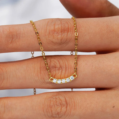 Collier chaîne pendentif cinq pierres en argent plaqué or jaune et diamants sur une main de femme.