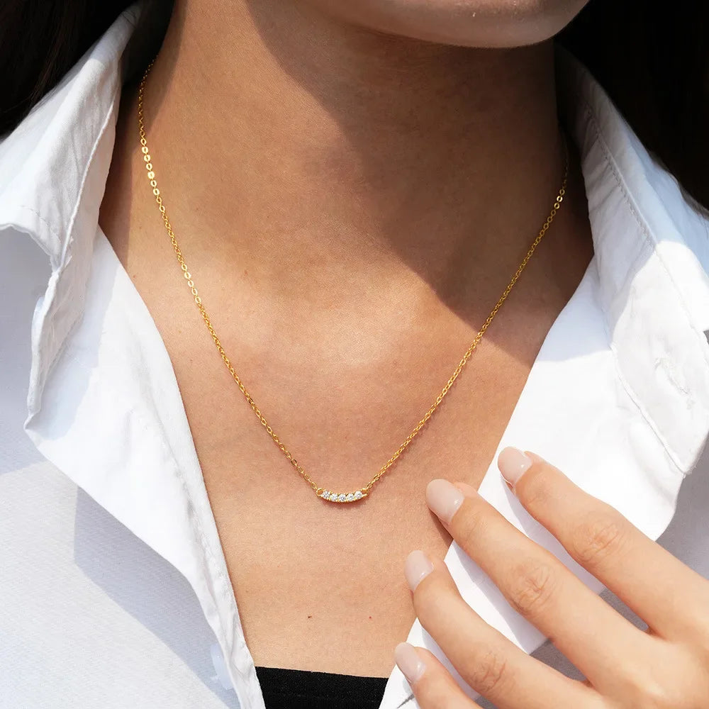 Collier chaîne pendentif cinq pierres en argent plaqué or jaune et diamants porté au cou d'une femme.
