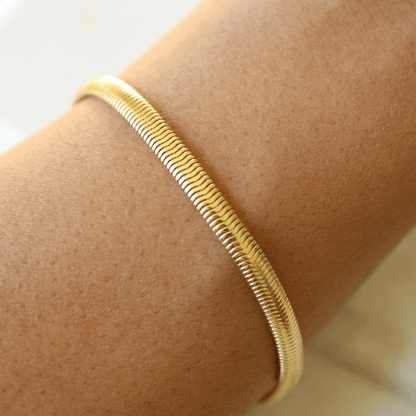 Chaîne serpent en argent plaqué or jaune portée au poignet d'une femme.