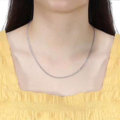 Chaîne torsadée en argent 925 plaqué or blanc portée au cou d'une femme vue de face.