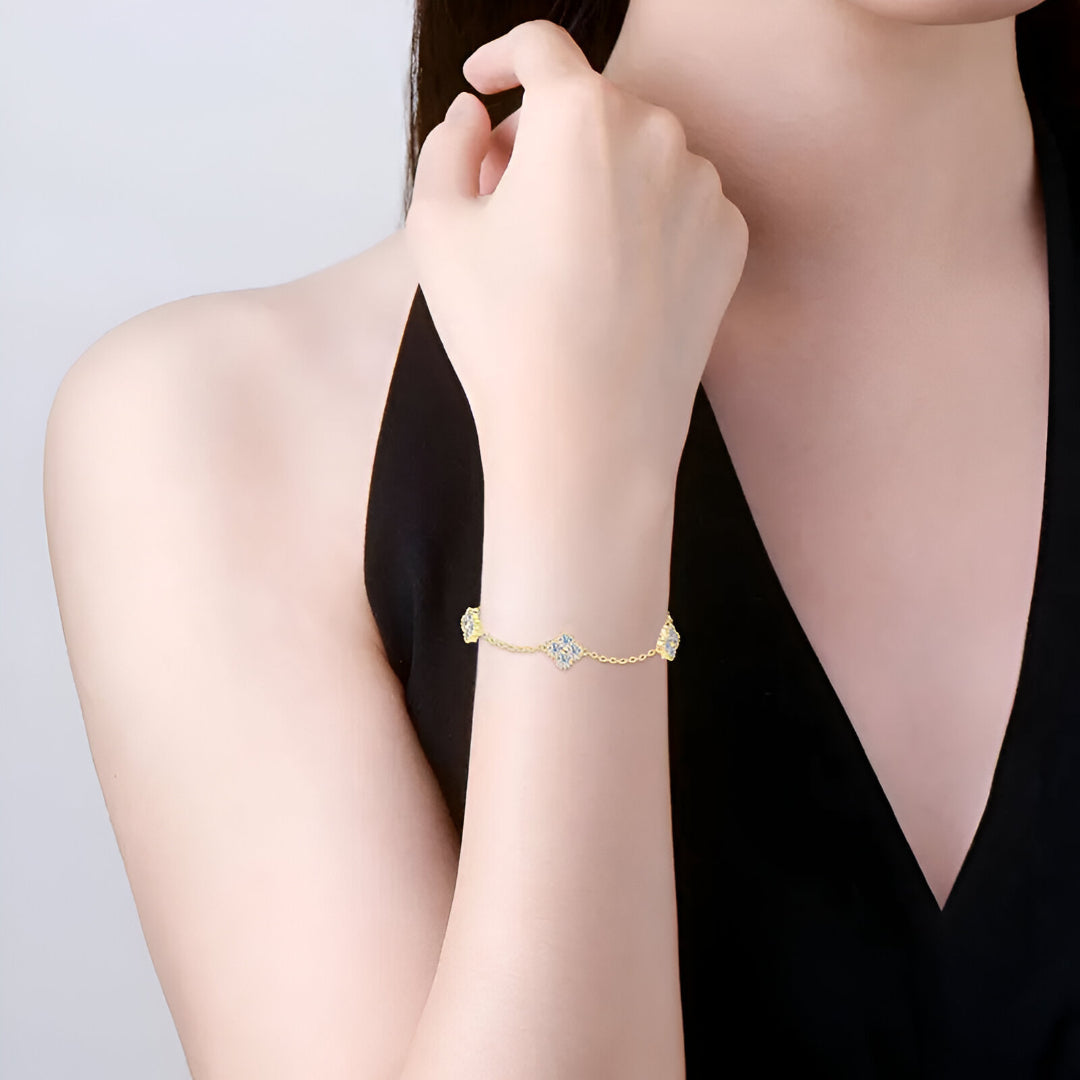 Chaîne trèfle à quatre feuilles en or jaune et diamants synthétiques portée au poignet d'une femme vue de face.