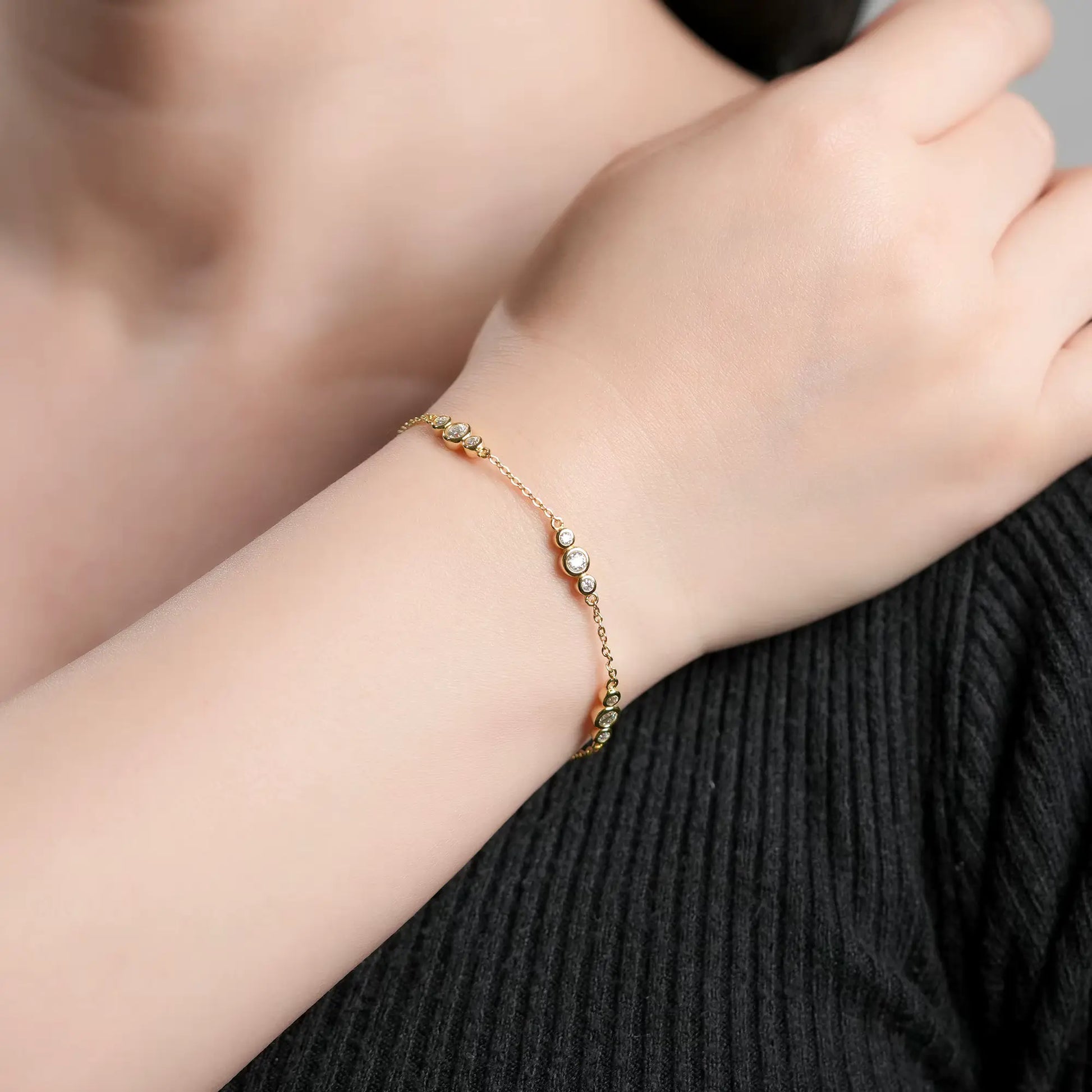 Chaîne triple pierres en or jaune et diamants synthétiques portée au poignet d'une femme.