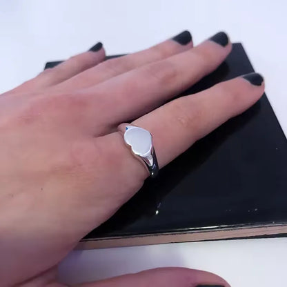 Chevalière cœur argenté en acier plaqué titane variante 12mm portée au doigt d'une femme vue du dessus.