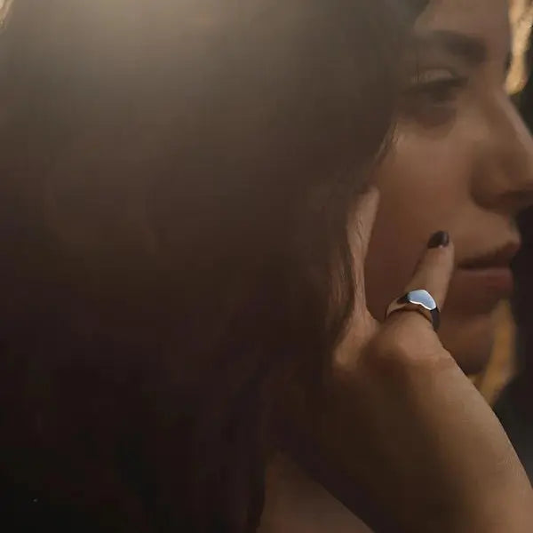 Chevalière cœur argenté en acier plaqué titane variante 12mm portée au doigt d'une femme.