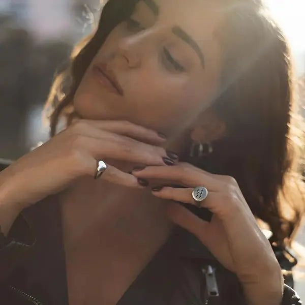 Chevalière cœur argenté en acier plaqué titane variante 12mm portée au doigt d'une femme vue de loin.