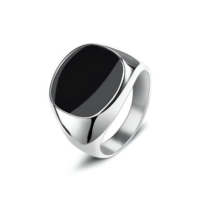 Chevalière moderne unisexe Nyx en acier inoxydable 316L plaqué or blanc 18K et onyx de forme elliptique sur fond blanc.