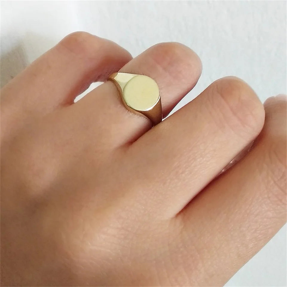 Chevalière pavé arrondi poli en acier inoxydable plaqué or jaune portée au doigt d'une femme vue du dessus.