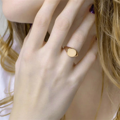 Chevalière pavé arrondi poli en acier inoxydable plaqué or jaune portée au doigt d'une femme vue de face.