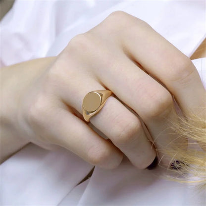 Chevalière pavé arrondi poli en acier inoxydable plaqué or jaune portée au doigt d'une femme vue de proche.