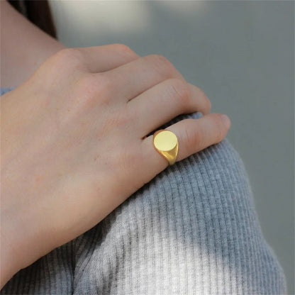 Chevalière pavé arrondi poli en acier inoxydable plaqué or jaune portée au doigt d'une femme.