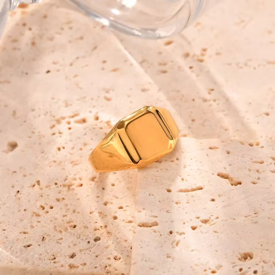 Chevalière pavé cubique poli en acier plaqué or jaune posée.