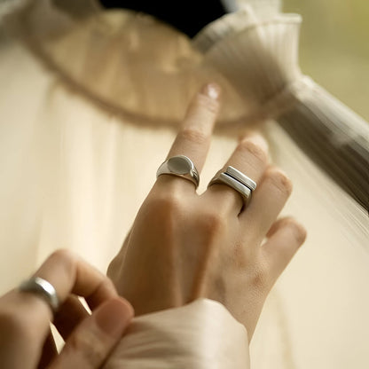 Bague chevalière pavé fin en acier plaqué or blanc portée au doigt d'une femme.