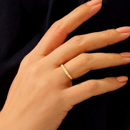 Bague chevalière pavé fin en acier plaqué or jaune portée au doigt 'une femme vue rapprochée.