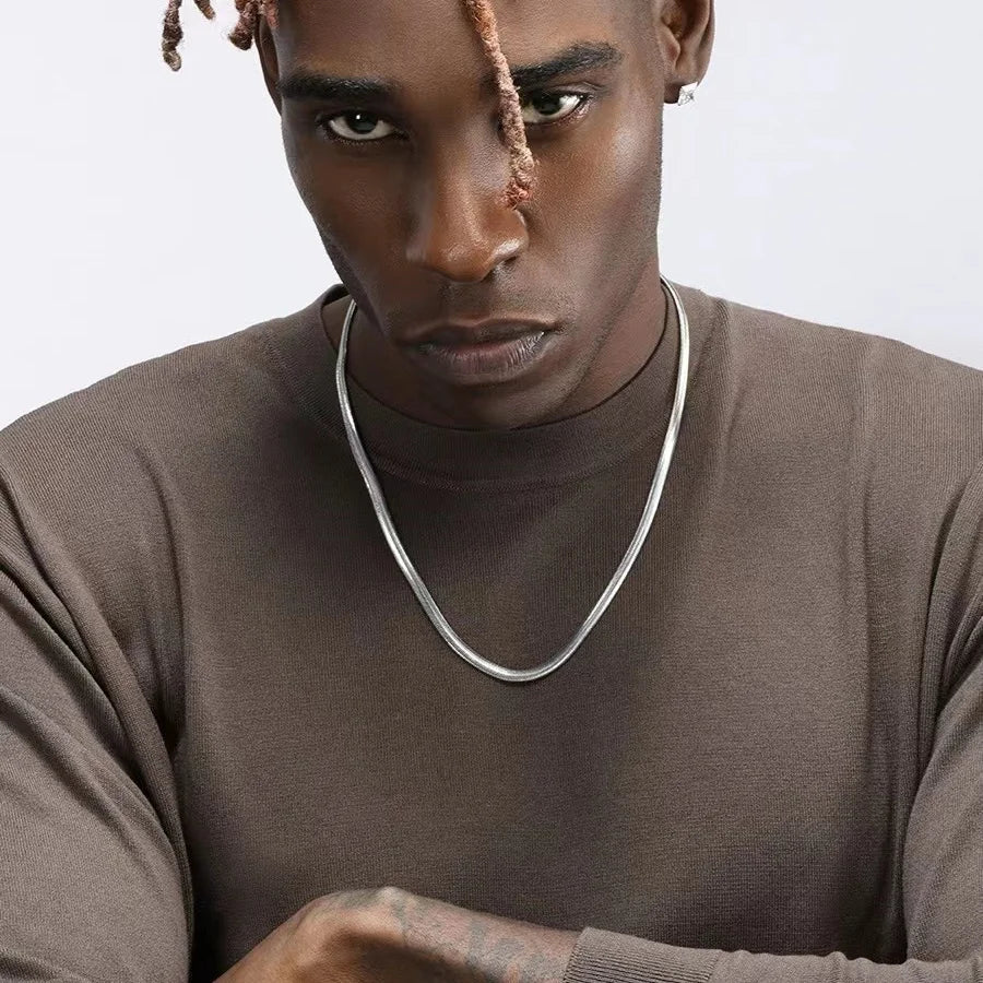 Collier à chaîne en acier inoxydable porté au cou d'un homme vue de loin.