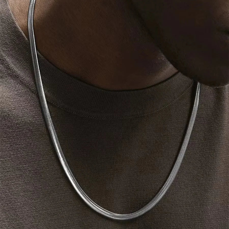Collier à chaîne en acier inoxydable porté au cou d'un homme vue de proche.