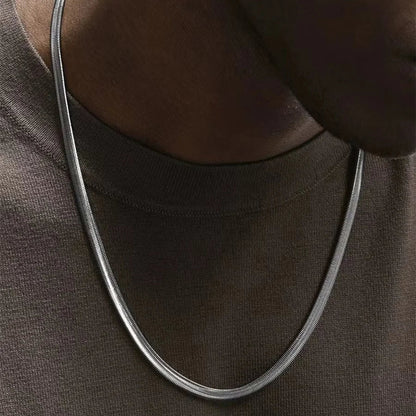 Collier à chaîne en acier inoxydable porté au cou d'un homme vue de proche.