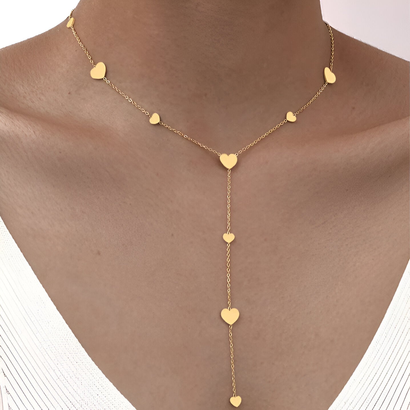 Collier cœur en acier inoxydable doré porté au cou d'une femme vue de face.