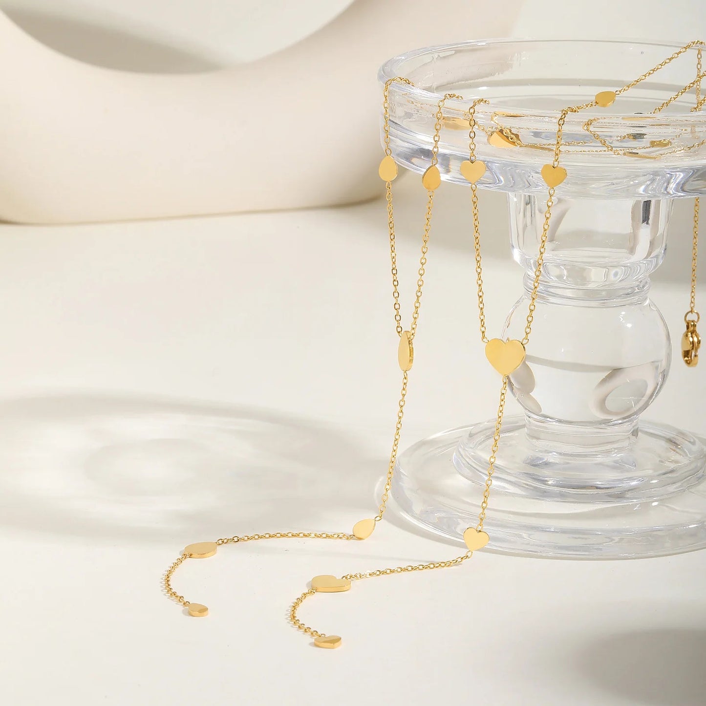 Collier cœur en acier inoxydable doré sur un verre.