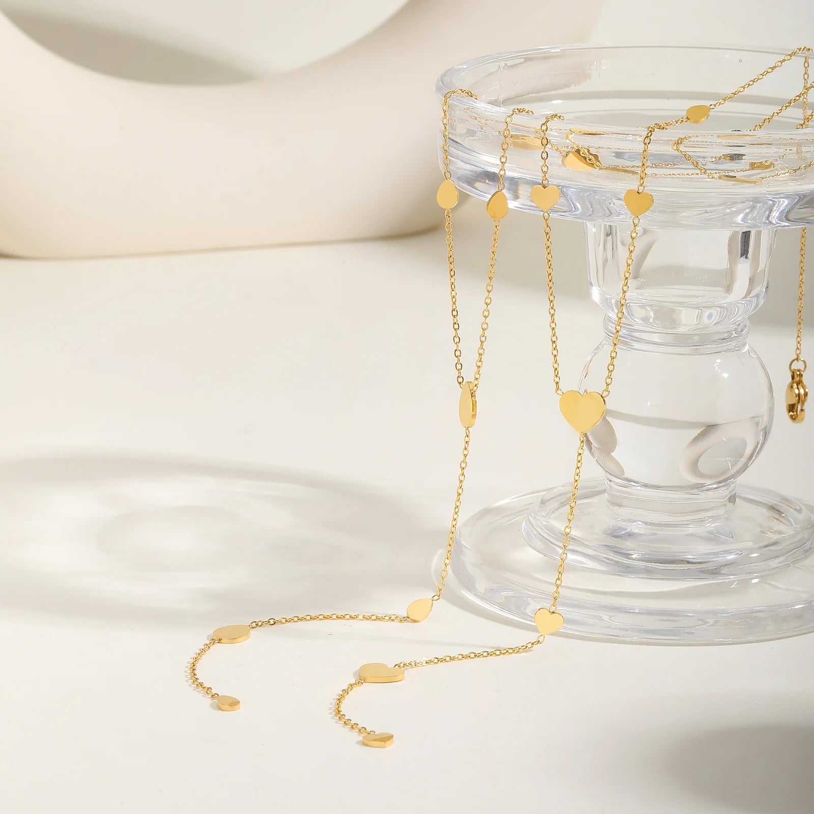 Collier cœur en acier inoxydable doré sur un verre.