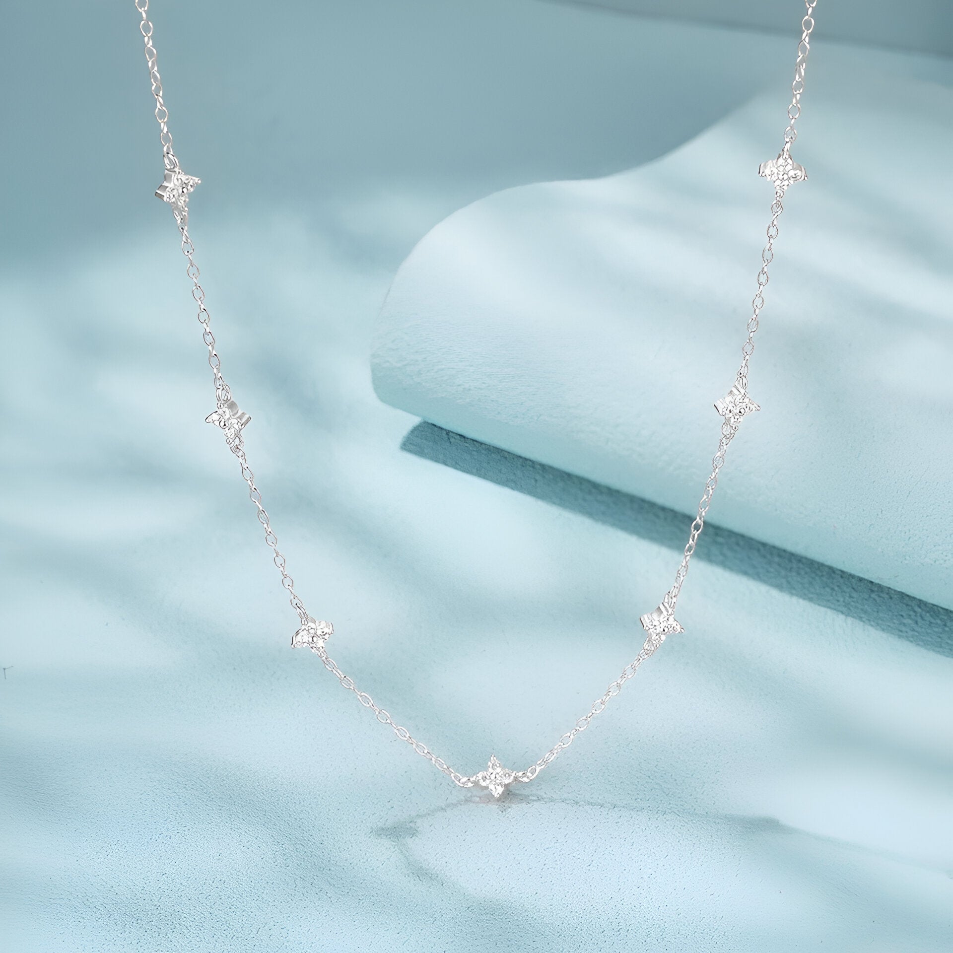 Détail du pendentif étoilé du Collier Constellation en argent 925 et or blanc 18k avec moissanite éclatante sur fond bleu – zoom chaîne or blanc