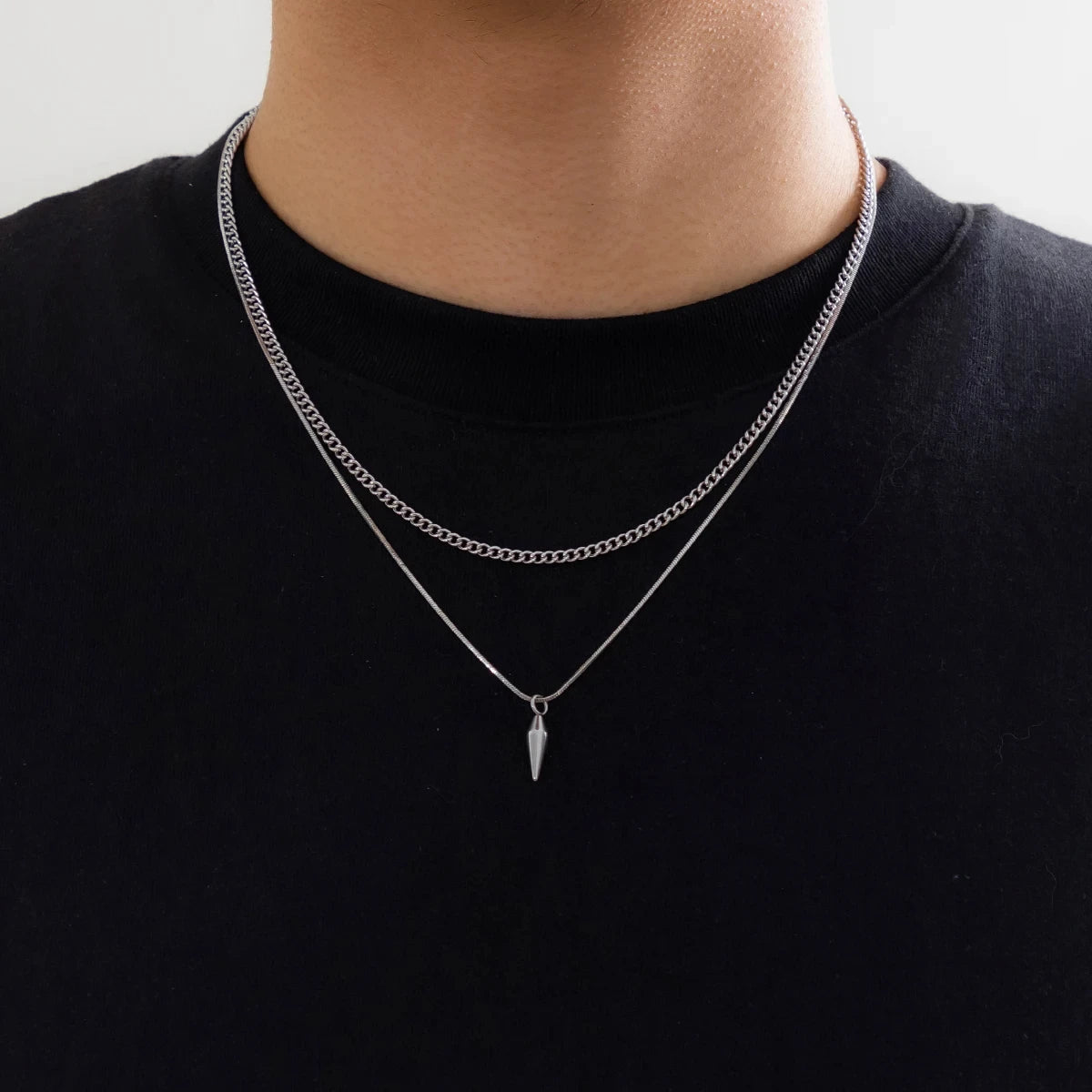 Collier double chaîne en acier inoxydable porté au cou d'un homme vue de loin.