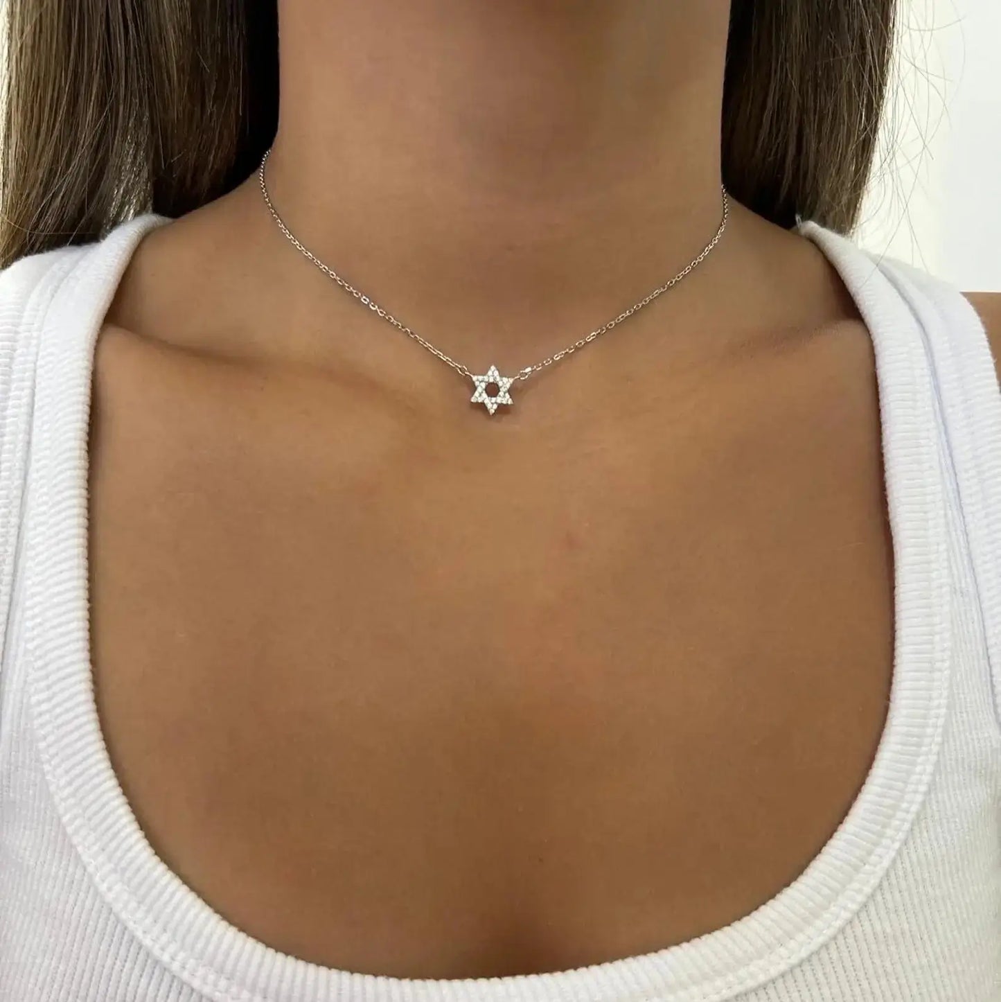 Collier étoile de david en argent 925 plaqué or blanc et diamants porté au cou d'une femme.