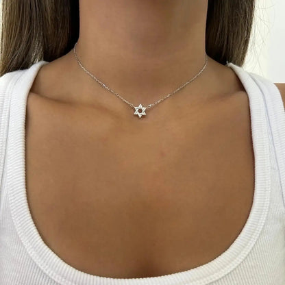 Collier étoile de david en argent 925 plaqué or blanc et diamants porté au cou d'une femme.