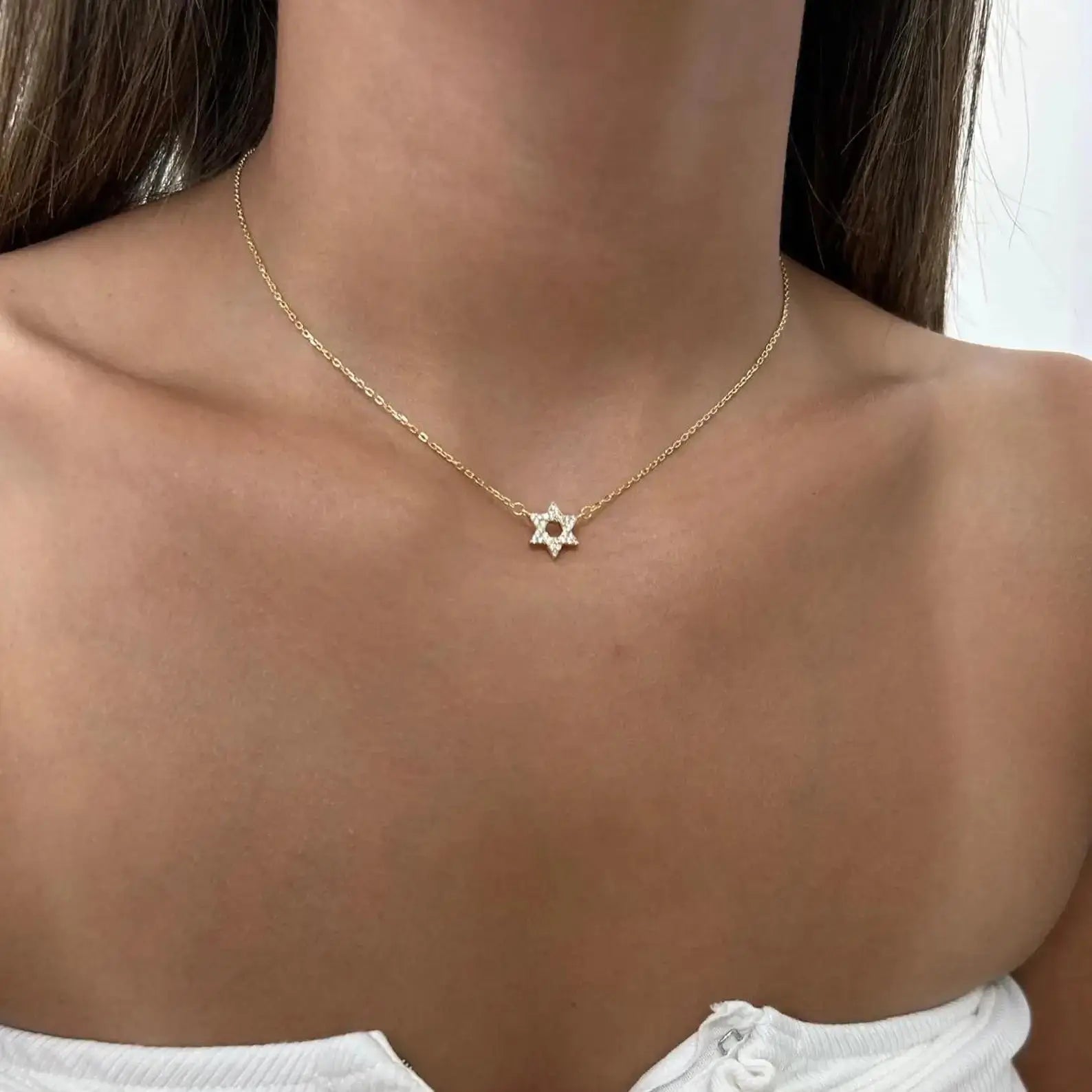 Collier étoile de david en argent 925 plaqué or jaune et diamants porté au cou d'une femme vue de face.