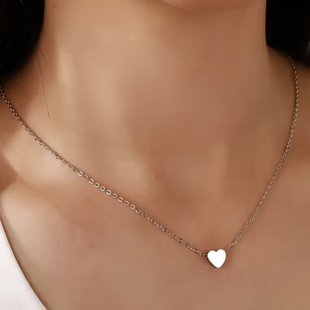 Collier fantaisie cœur en or blanc porté au cou d'une femme.