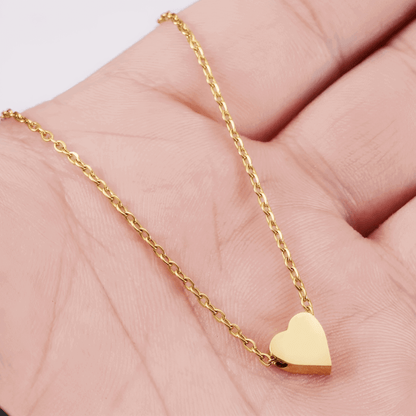 Collier fantaisie cœur en or jaune montré par une main de femme.