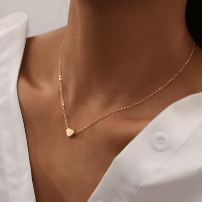 Collier fantaisie cœur en or jaune porté au cou d'une femme vue de côté.