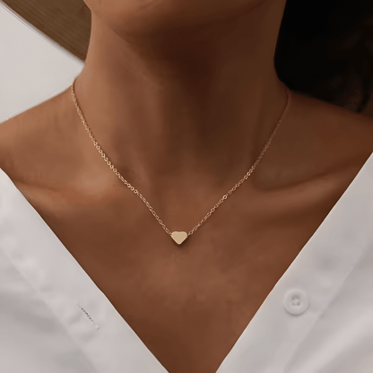 Collier fantaisie cœur en or jaune porté au cou d'une femme vue de face.
